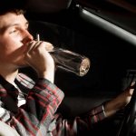 man drinks and smokes while driving