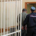 policeman escorts a man out of the courtroom